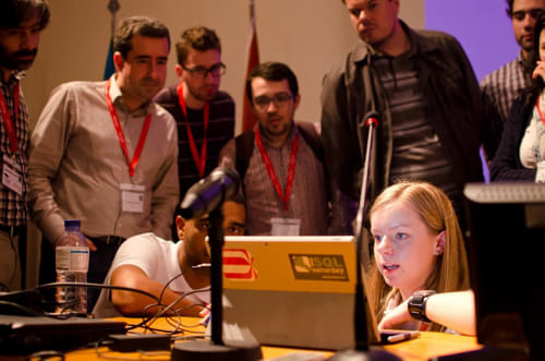 Cathrine sitting on the floor in front of her laptop with a crowd of people around her.