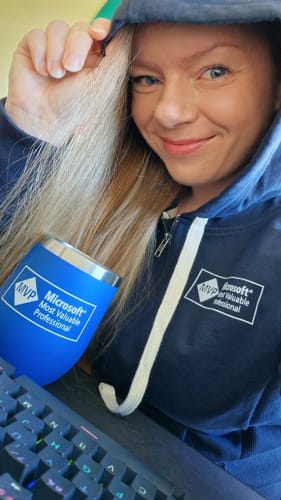 Cathrine Wilhelmsen wearing an MVP hoodie, sitting by her keyboard with an MVP coffee mug.